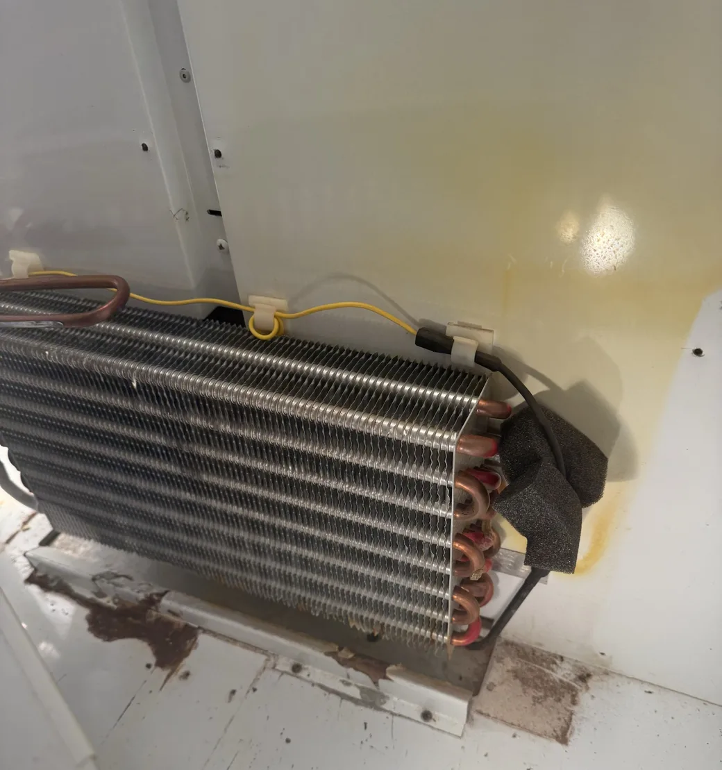 Refrigeration coil and copper tubing visible through an open appliance access area